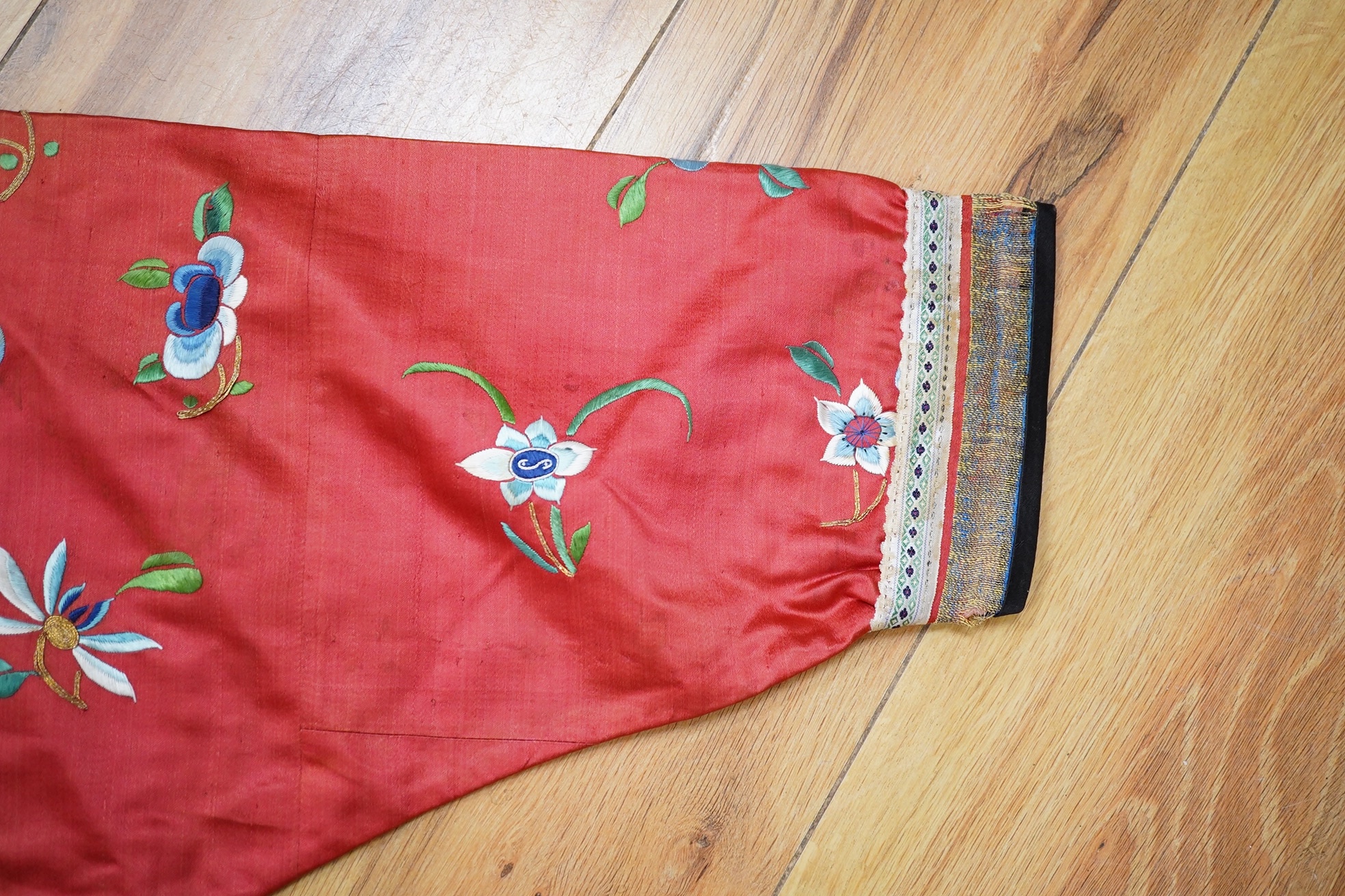 A Chinese embroidered fan case, a small red silk embroidered robe, trousers and a later pair of embroidered slippers, the robe possibly for a child, 20th century, embroidered with multi-coloured flowers and gold thread o